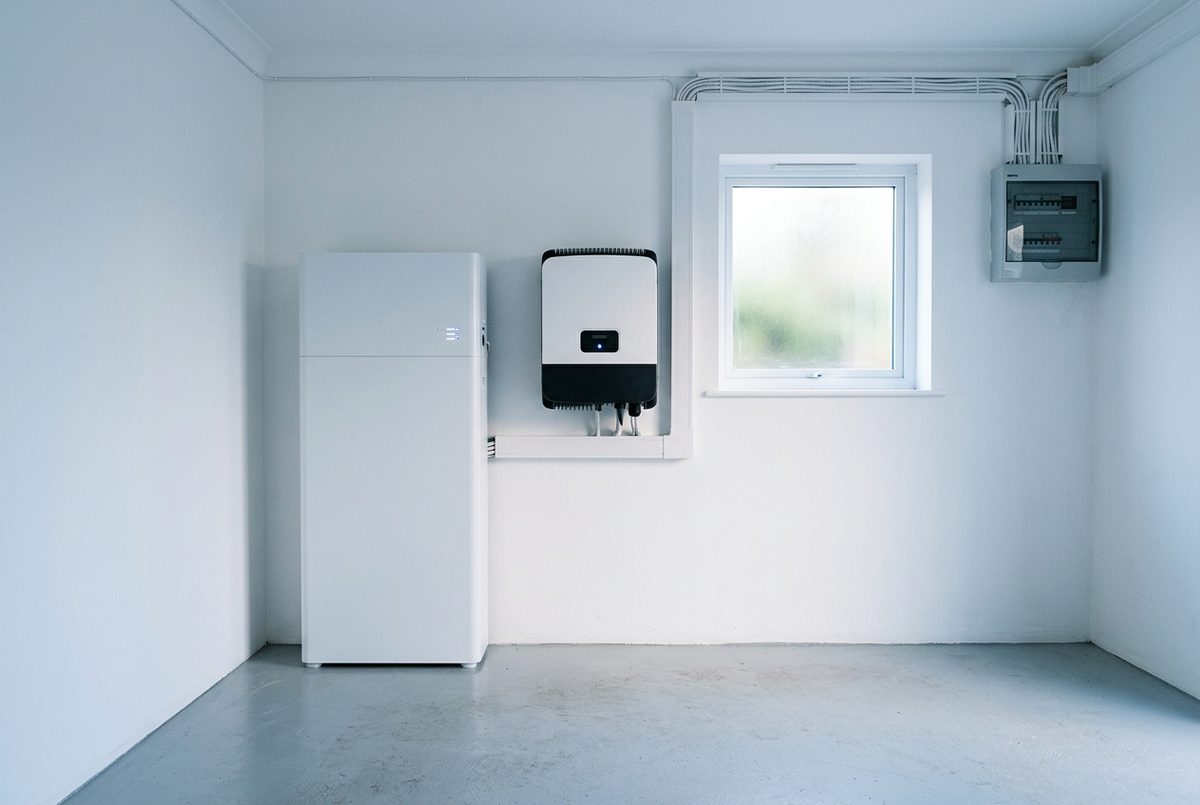 Weisser Stromspeicher und Wechselrichter an der Wand eines hellen Technikraums