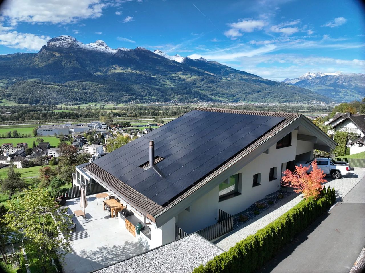 Einfamilienhaus mit Vollflächen-Photovoltaikanlage vor Bergpanorama im Rheintal