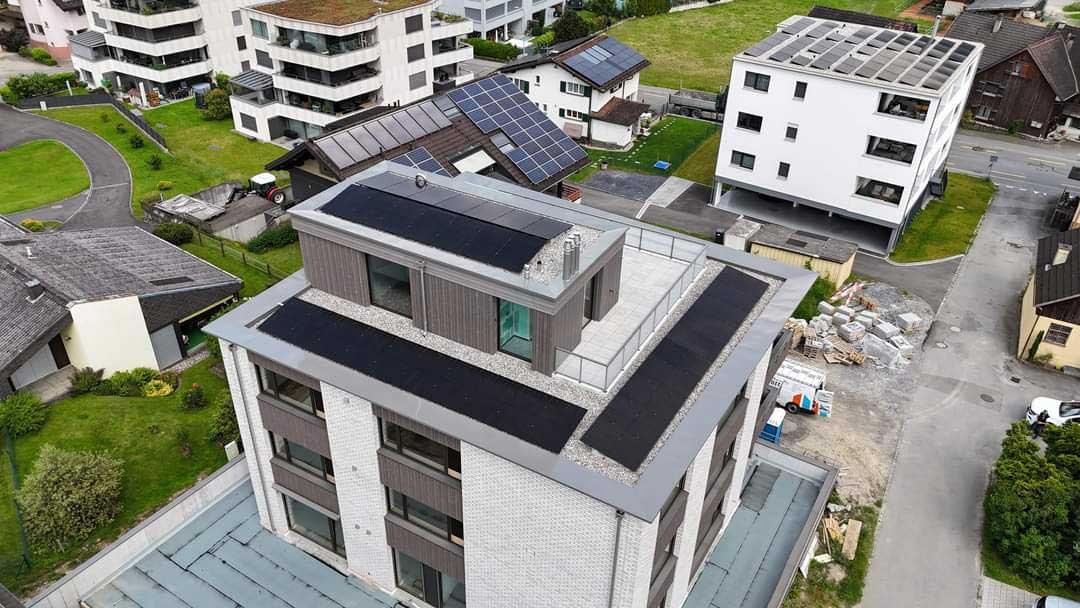 Luftaufnahme eines Mehrfamilienhauses mit Photovoltaikmodulen auf dem Flachdach in Mauren