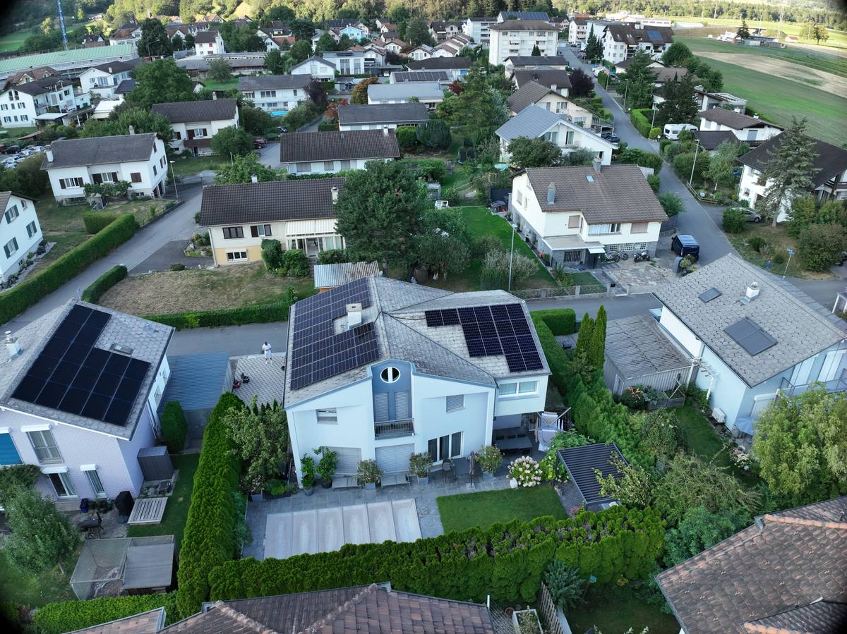 Luftaufnahme eines Wohnquartiers, im Vordergrund ein Haus mit Photovoltaikanlage auf beiden Dachflächen