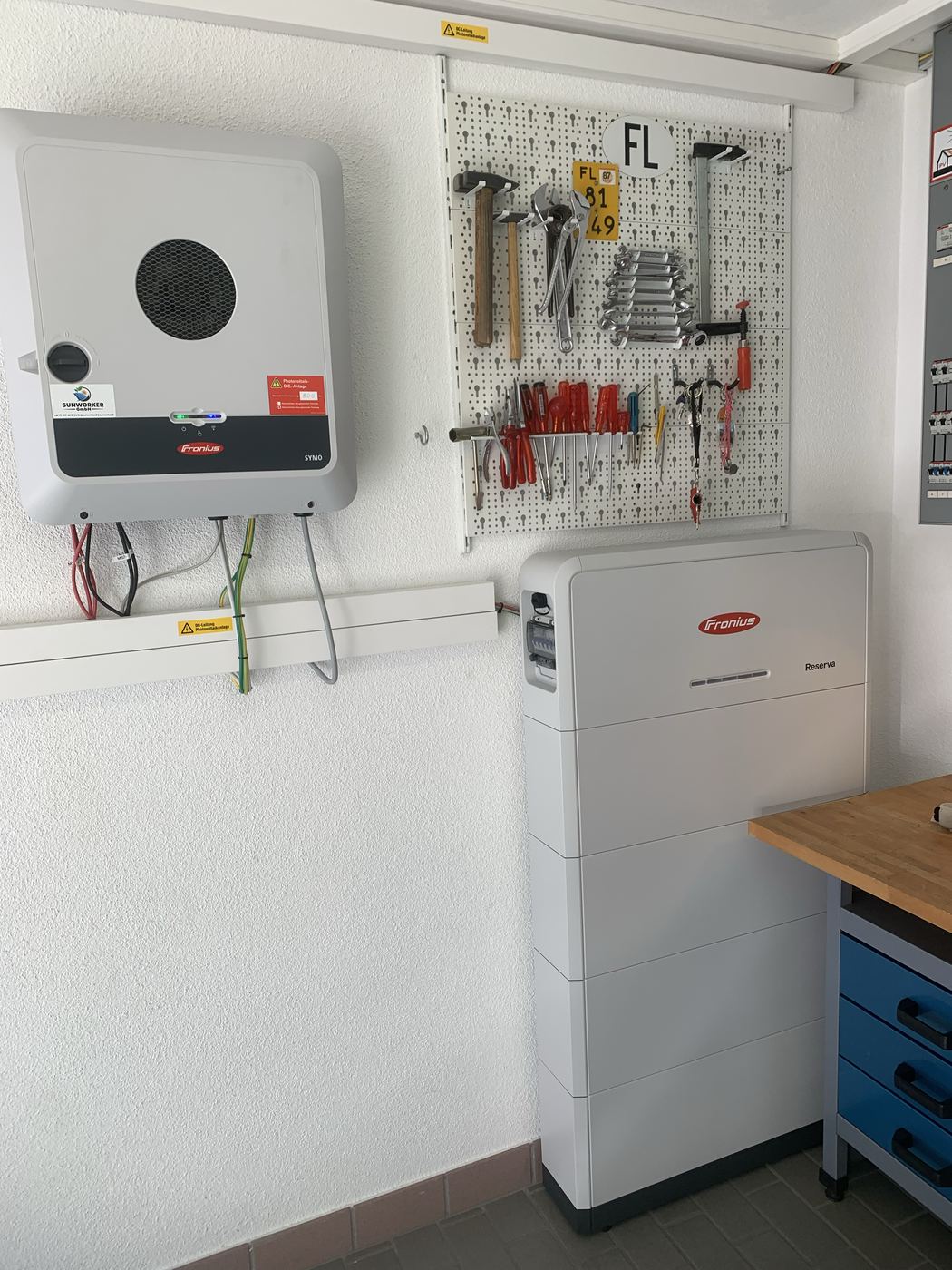 Technikraum mit Wechselrichter an der Wand und danebenstehendem Batteriespeicher